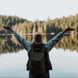 woman open her arms facing calm body of water