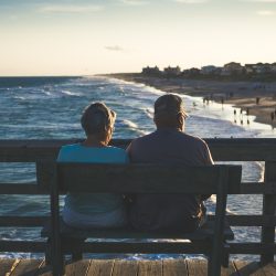 man and woman sitting on bench in front of beach